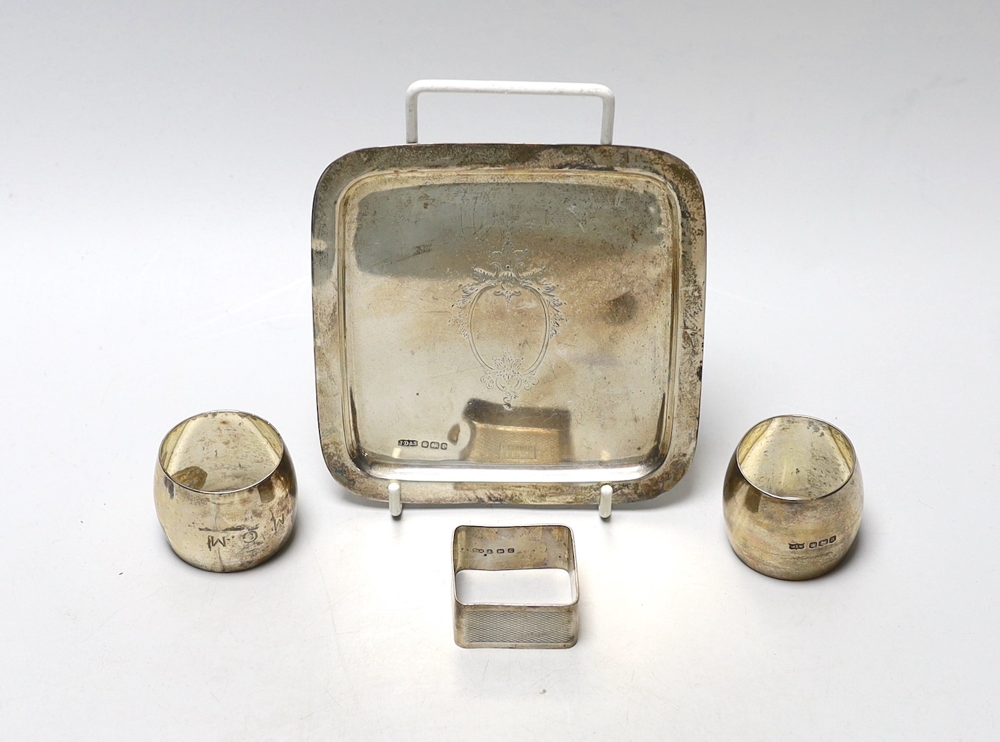 A George V small square silver dish by James Dixon & Sons and three silver napkin rings.